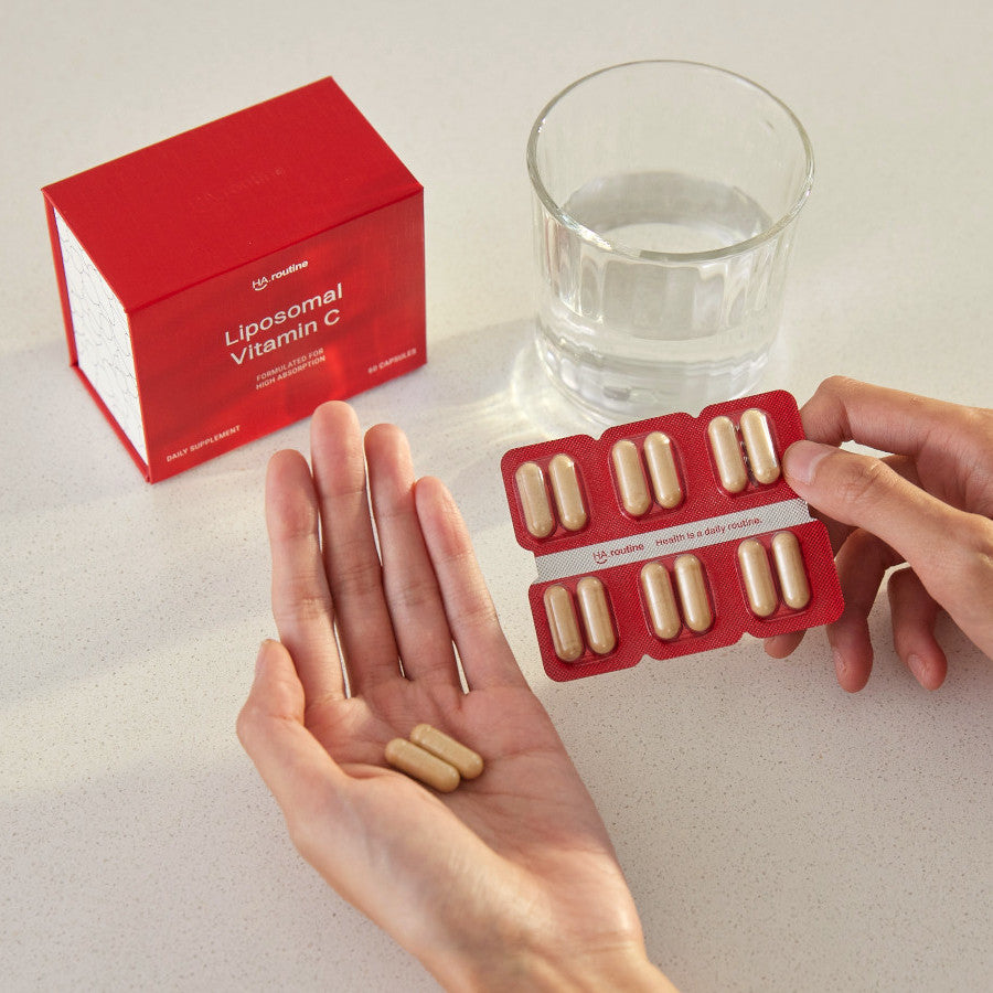 holding haroutine liposomal vitamin c capsules with a glass of water